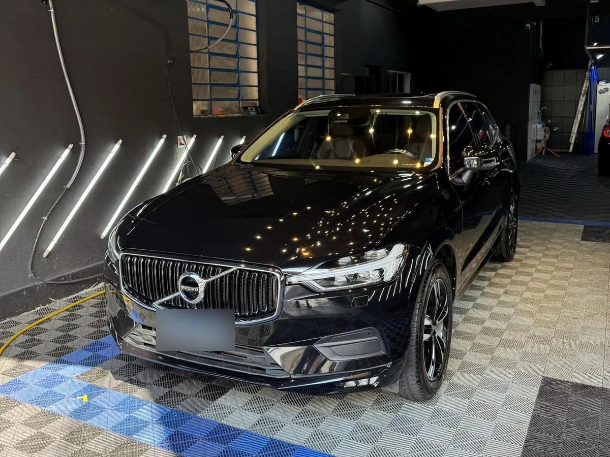 SUV Volvo XC60 preto finalizado no box da Resiliência, com a pintura refletindo a iluminação do teto.