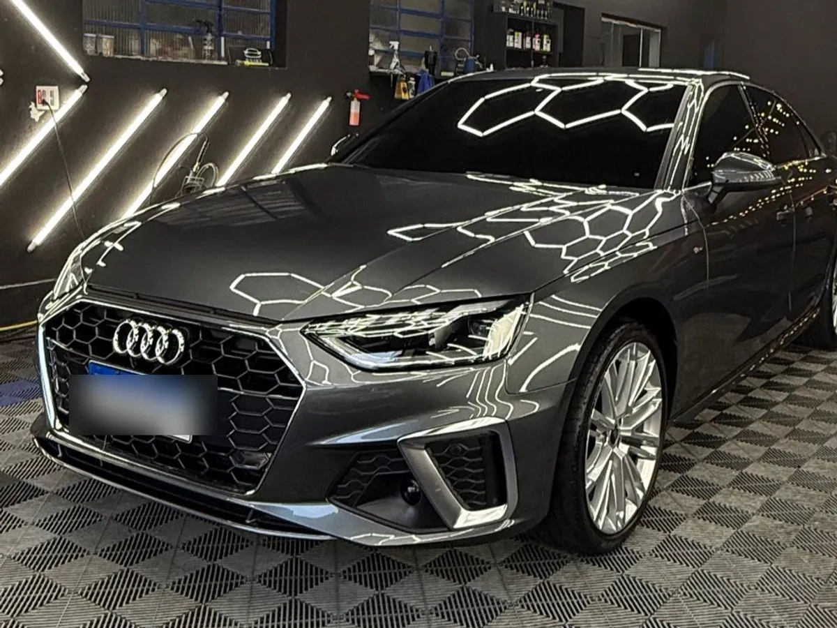 Audi A4 cinza-chumbo finalizado no box da Resiliência, com a pintura refletindo as luzes de LED.